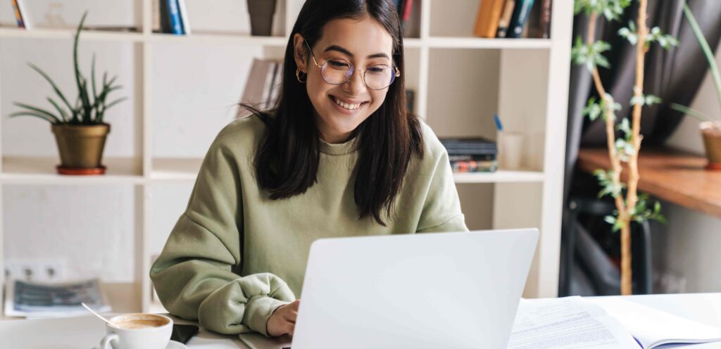 lady smiling while sitting at a desk look at a laptop